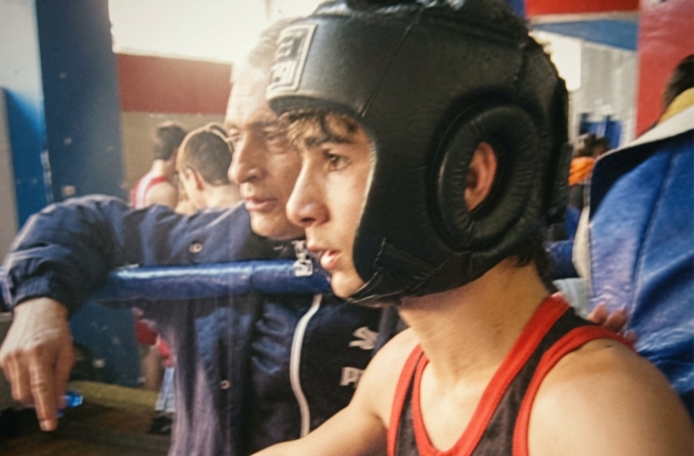 Artur in headgear at a kickboxing competition with his father behind him